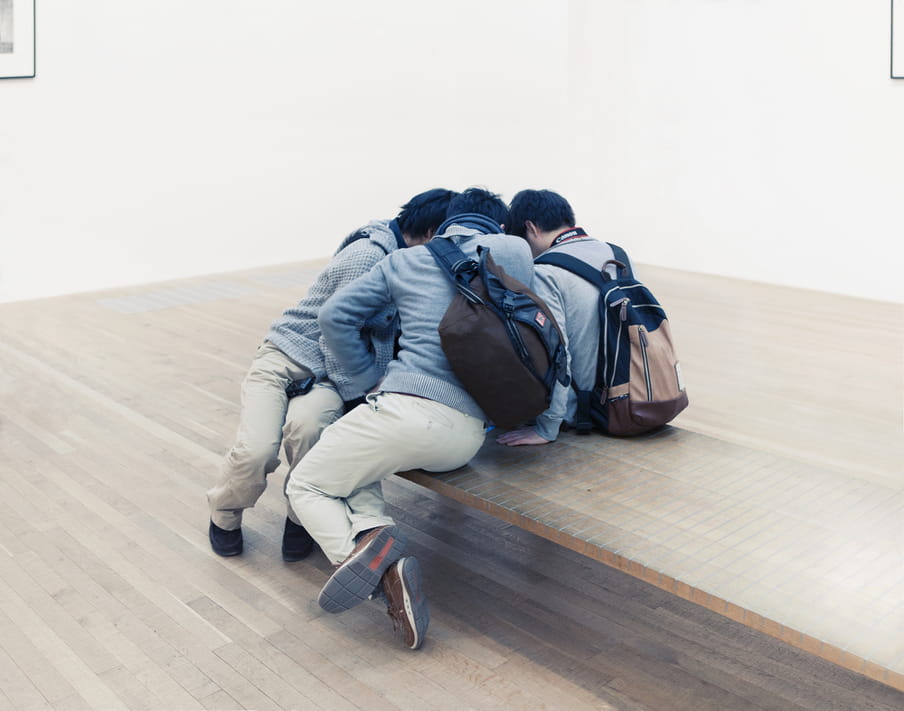 Photo of a few men sitting closely together in a museum