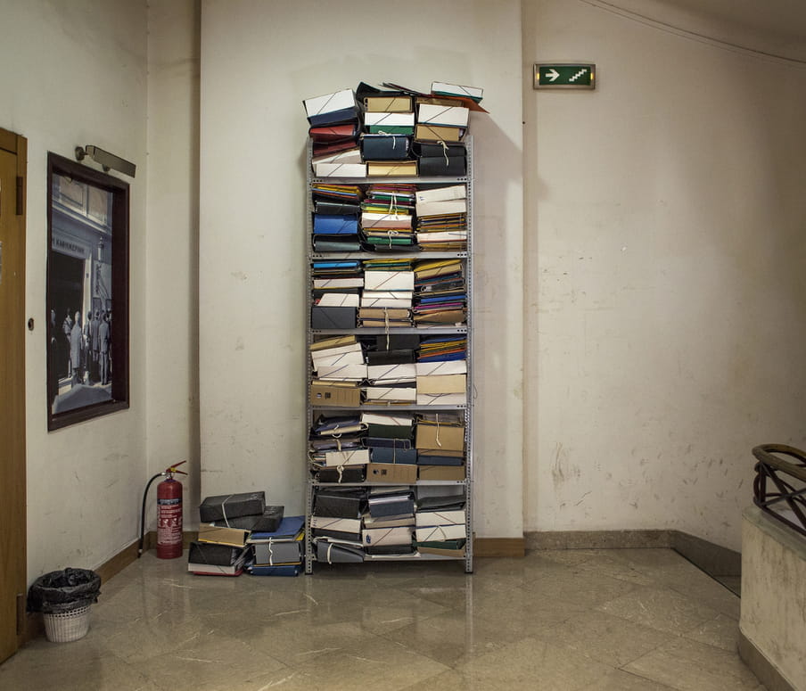 A filing cabinet stuffed with old files in a rundown stairwell. 