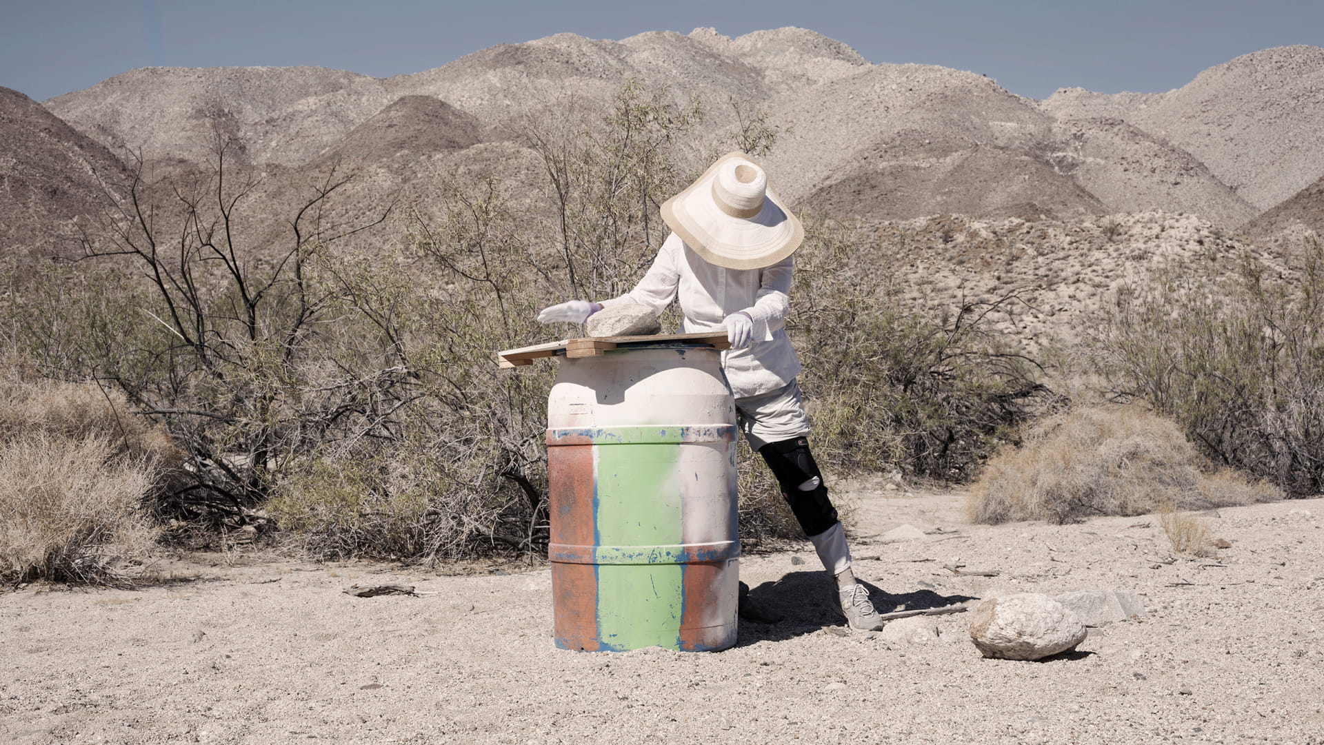 The leader of Water Station covering one of the water stations with wood and a rock to safeguard the bottles of water.