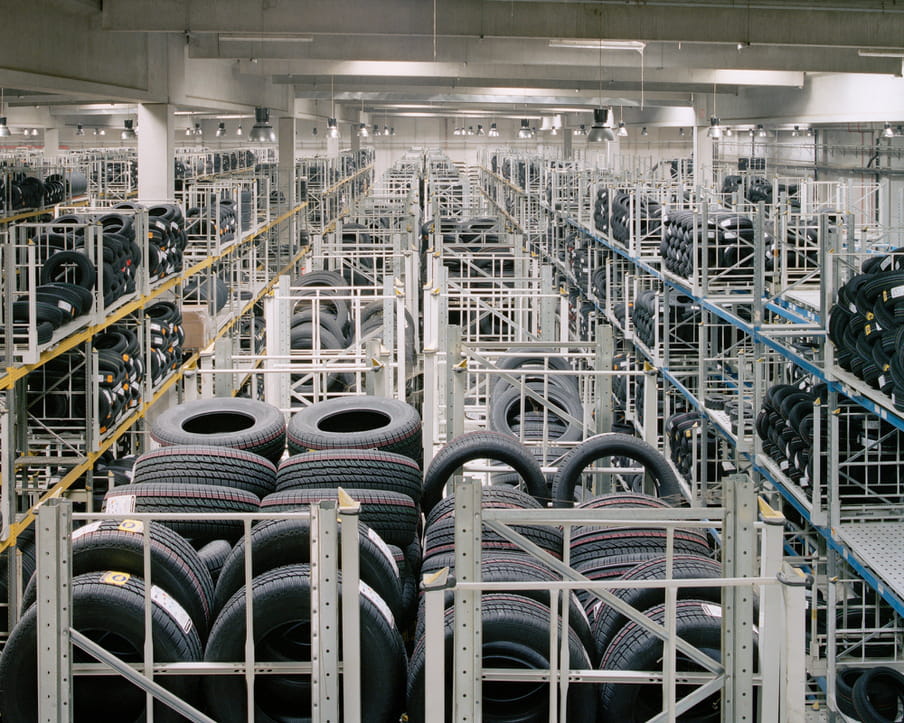 Colour photograph of a warehouse showing piles of tires. 