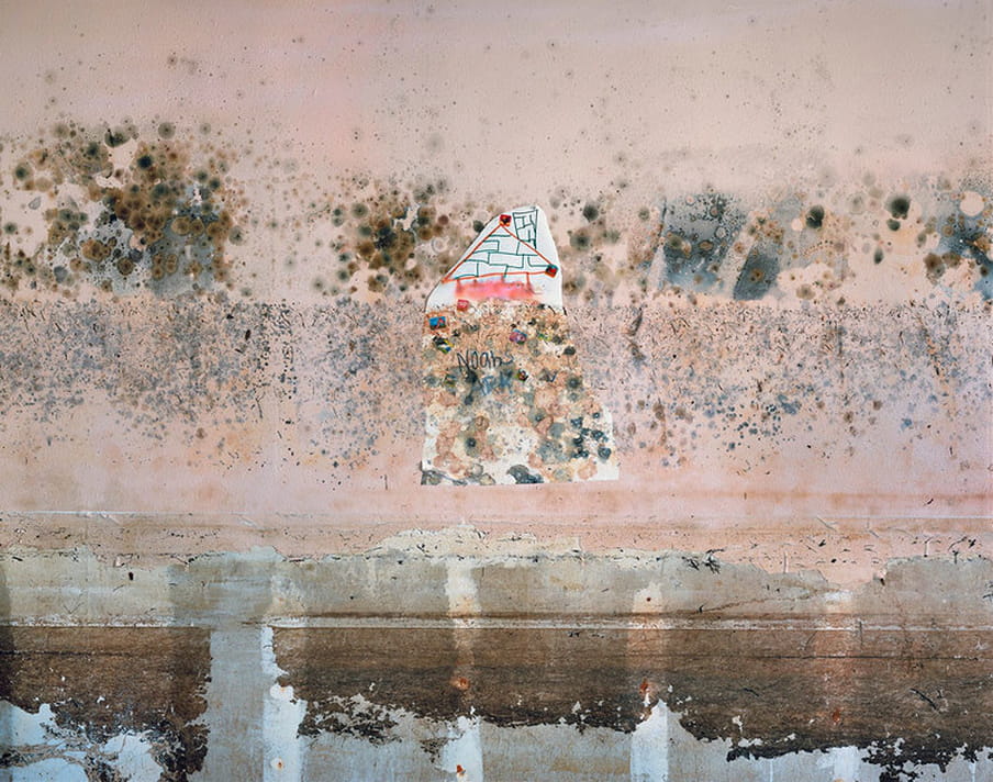 Photo of a wall with a drawing made by a child, destroyed by water damage. 