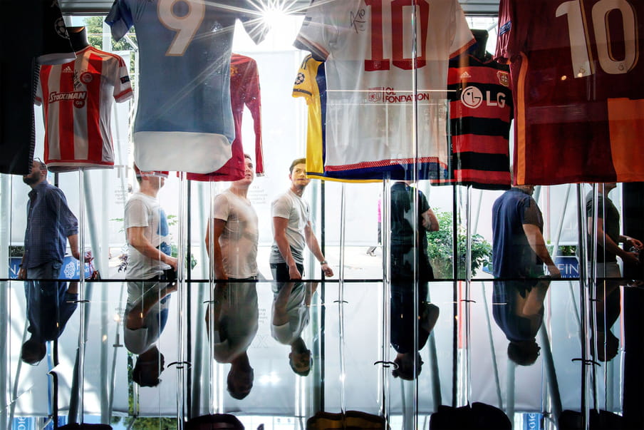 Photo of people visiting a football club museum and looking at football teams’ T-shirts