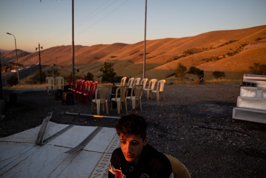 Photograph with a man at the centre and, in the background, a desert landscape with chairs