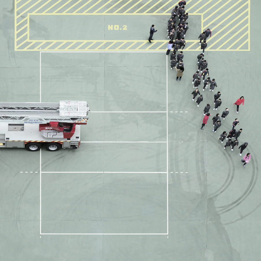 Photograph taken from above on a mint green court showing a group of people near a firetruck.