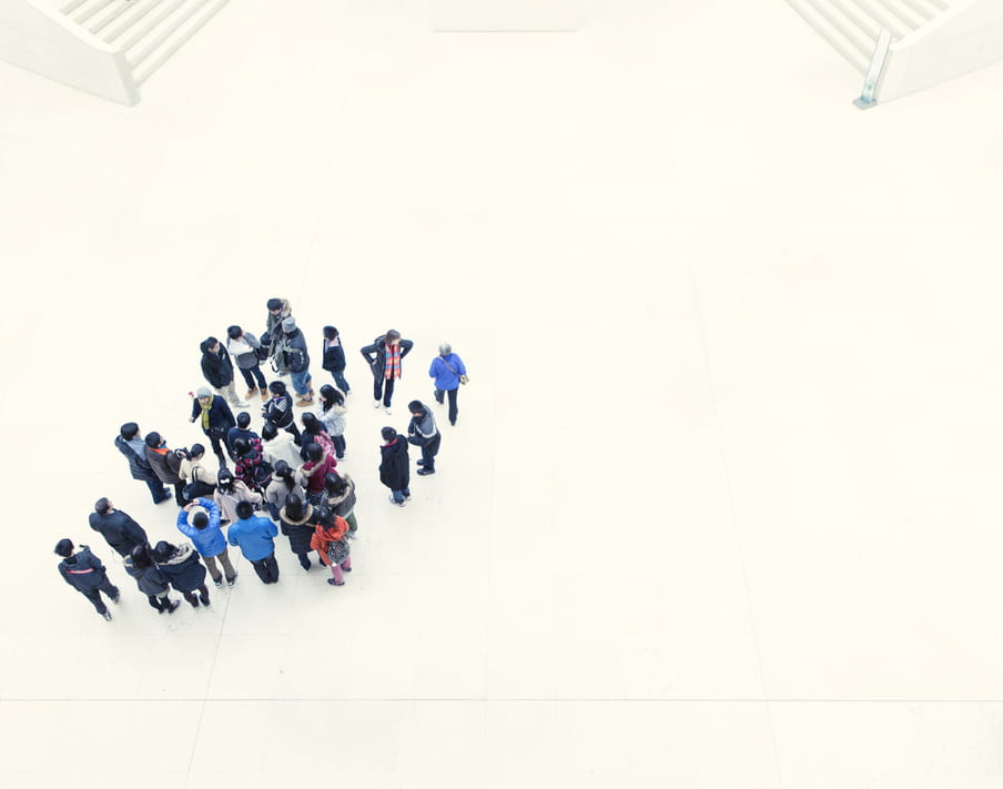 Group of people standing close together on a big, white square