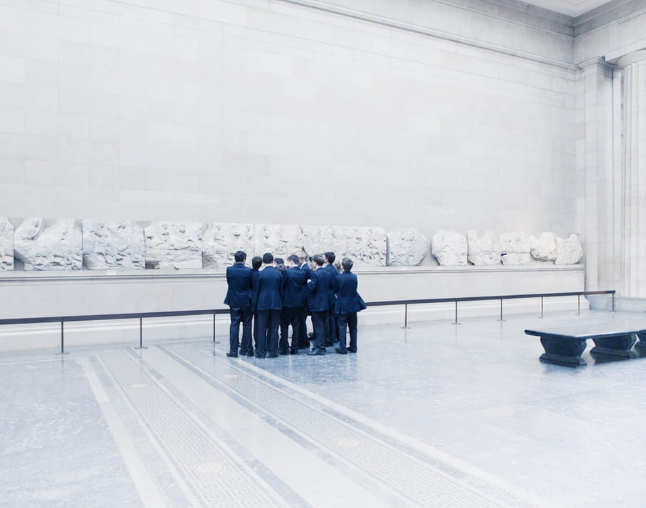 Group of men in suiting standing close together in a museum