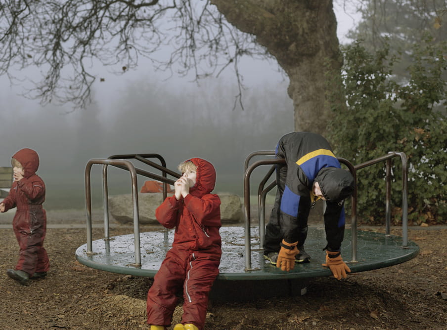 Photo of boys playing, wearing winter suits, on a playground