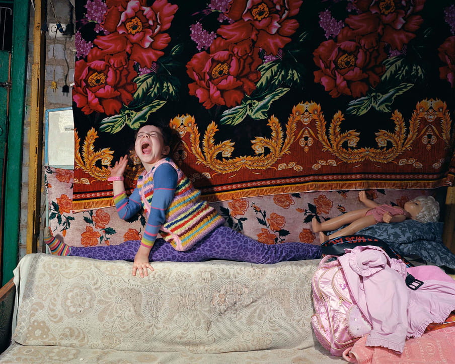 Photo of a young girl playing on a couch screaming. 