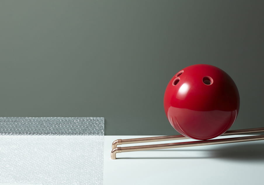 Colour photograph of a red bolling ball about to roll over a piece of bubble paper.