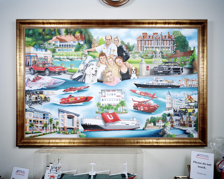 Picture of a painting showing a family surrounding by large mansions, boats and cars