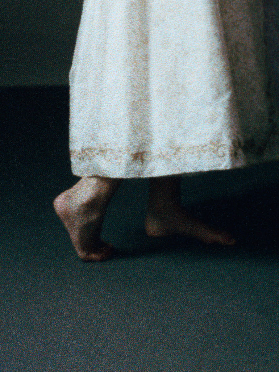 Close up of a girls feet, standing on her toes, in a white/yellow dress