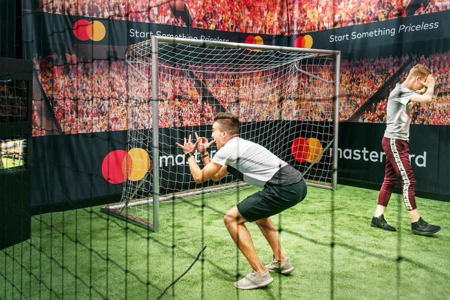 Photo of two young people in a fake football field imitating famous players’ gesture of victory