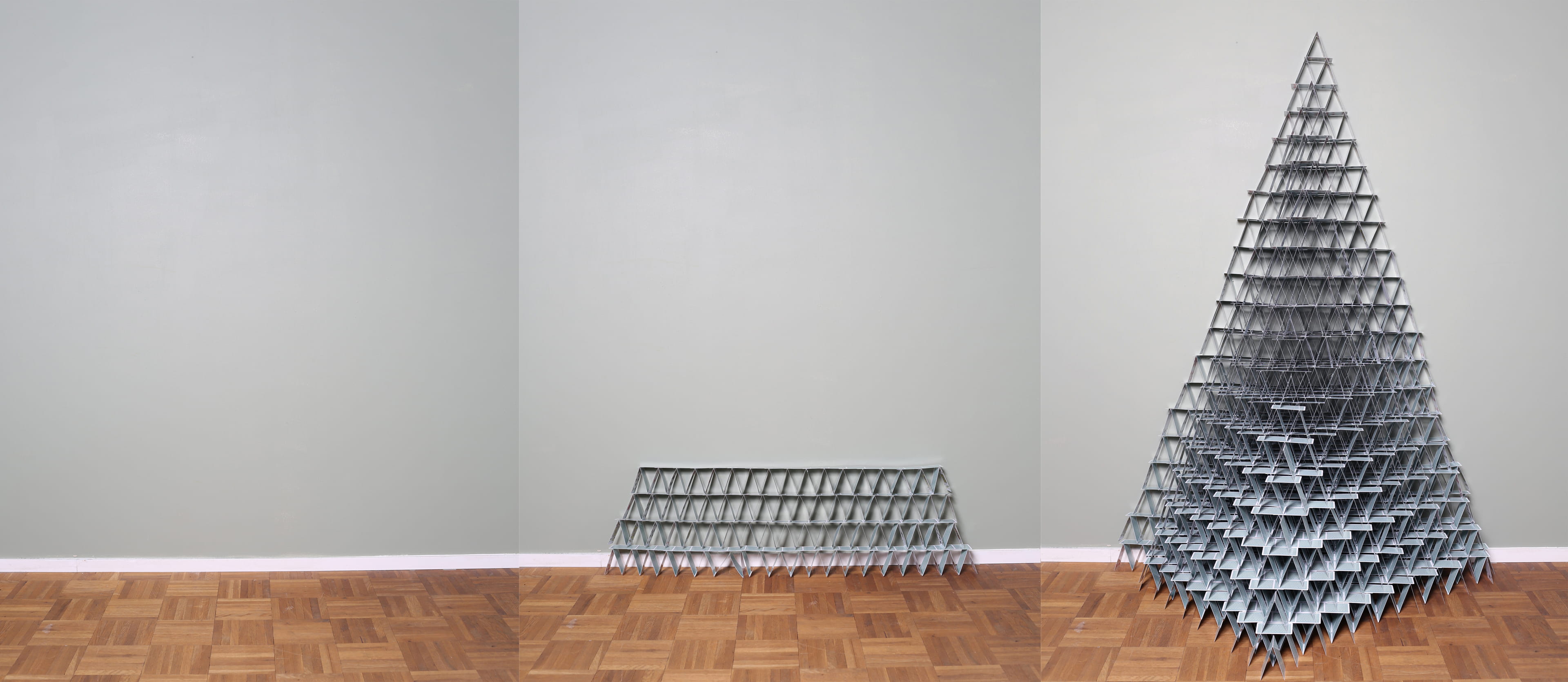 Image composed of three photographs all showing a light grey wall, a white baseboard and a parquetry floor. The photograph on the left is empty. The one in the middle shows a stack of bluish playing cards arranged in a 4 layers flat structure. The one on the right shows a huge pyramid made of the same card deck.