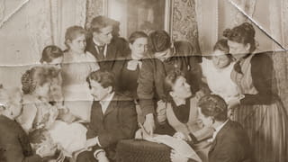 Old photo of people sitting together, damaged and folded