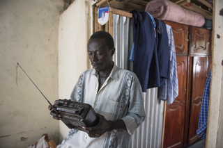 Thomas Ali listens to the radio to keep up with the international news. Juba, South Sudan. Photo by Charles Lomodong for De Correspondent
