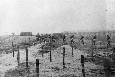Soldiers make their way across a series of barbed wire defenses in WWI, c. 1915. Photo by Getty Images